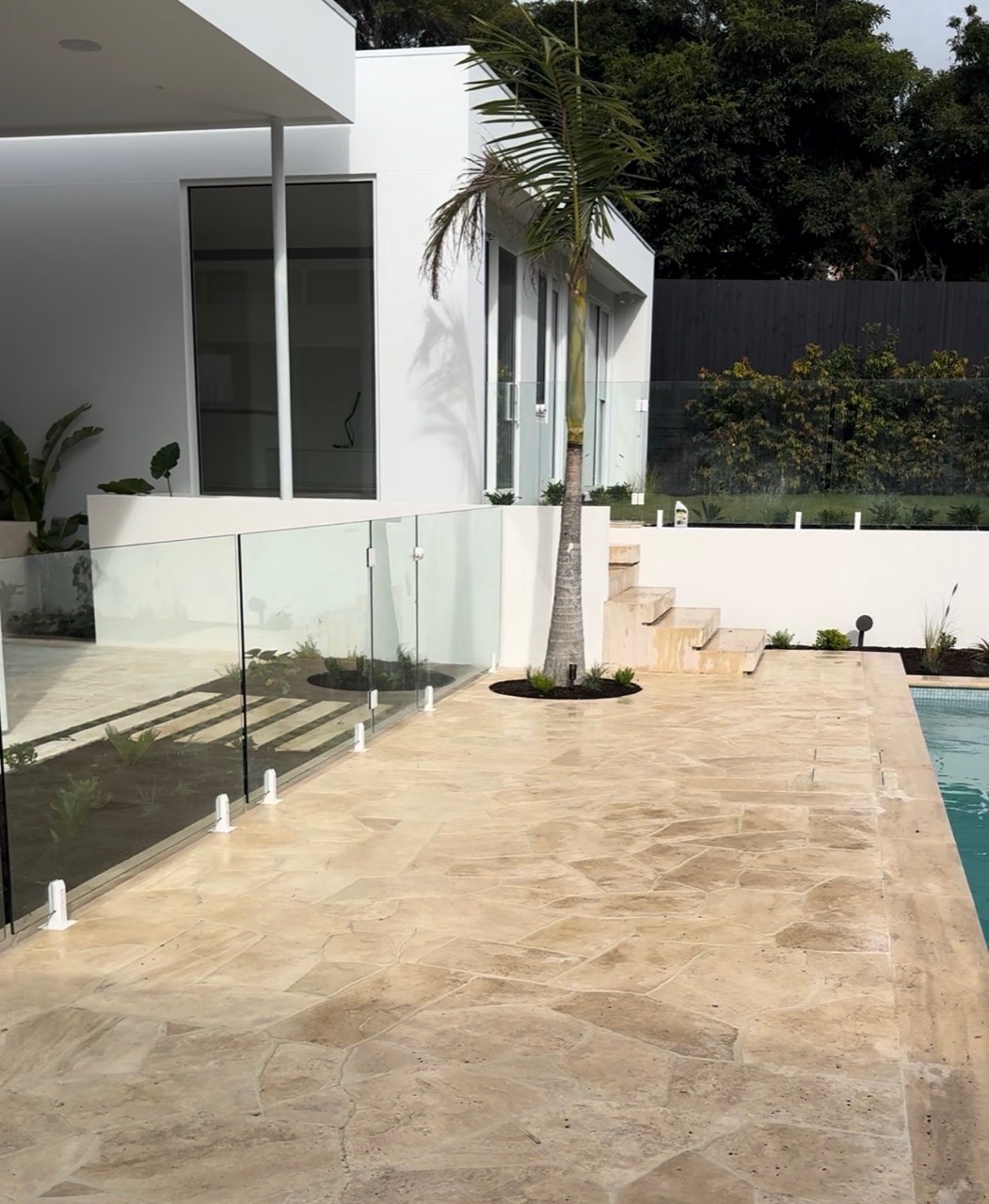 Warm natural stone crazy paving around a modern pool and landscaped residence in Mt Eliza